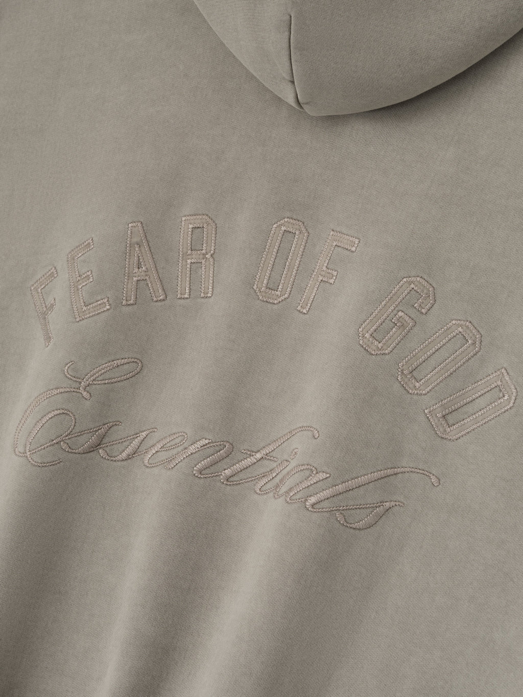 Close-up of smoke grey Embroidered Classic Full Zip Hoodie showing tonal Fear of God Essentials logo on hood section