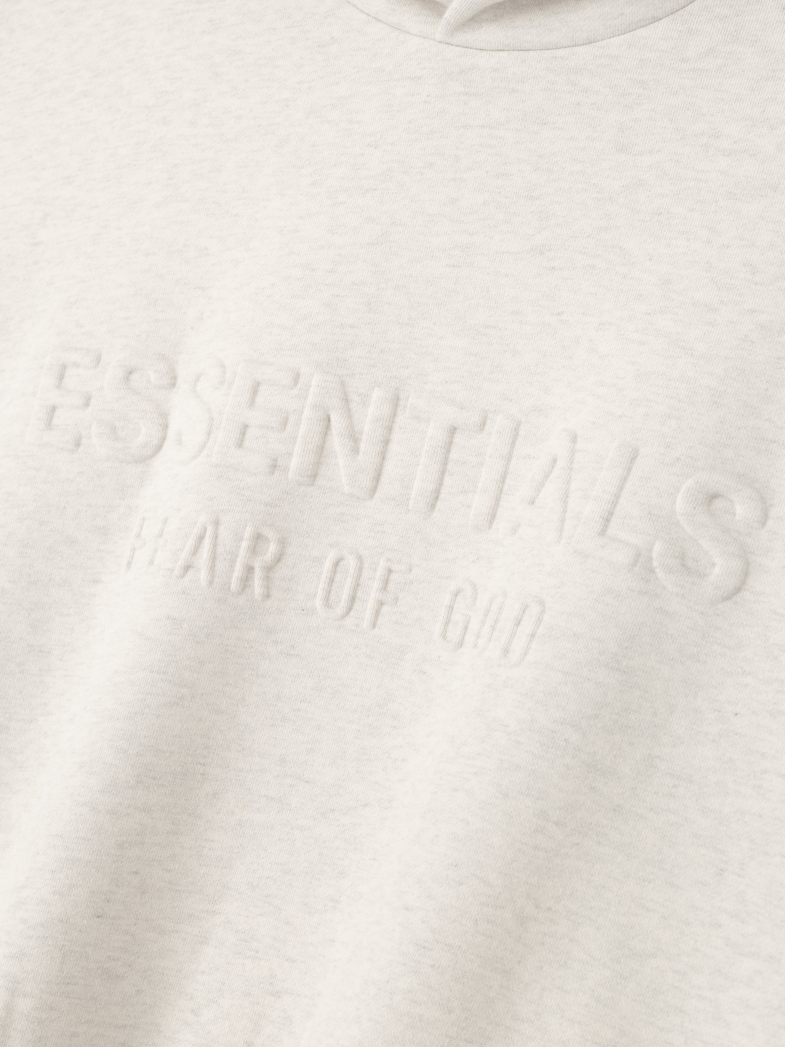 Close-up of oatmeal heather Embossed Essentials Classic Hoodie showing raised Fear of God logo detail on fabric