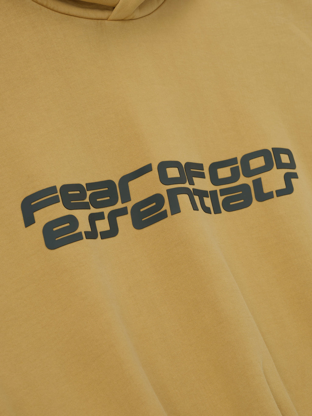 Close-up of canyon-colored cropped relaxed hoodie with large dark grey Fear of God Essentials logo across chest