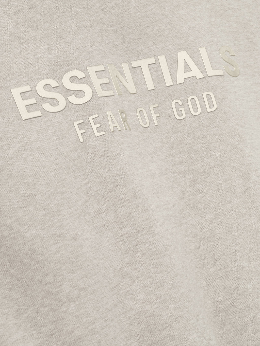 close-up of embossed ESSENTIALS Fear of God logo on soft light beige fleece fabric of classic hoodie