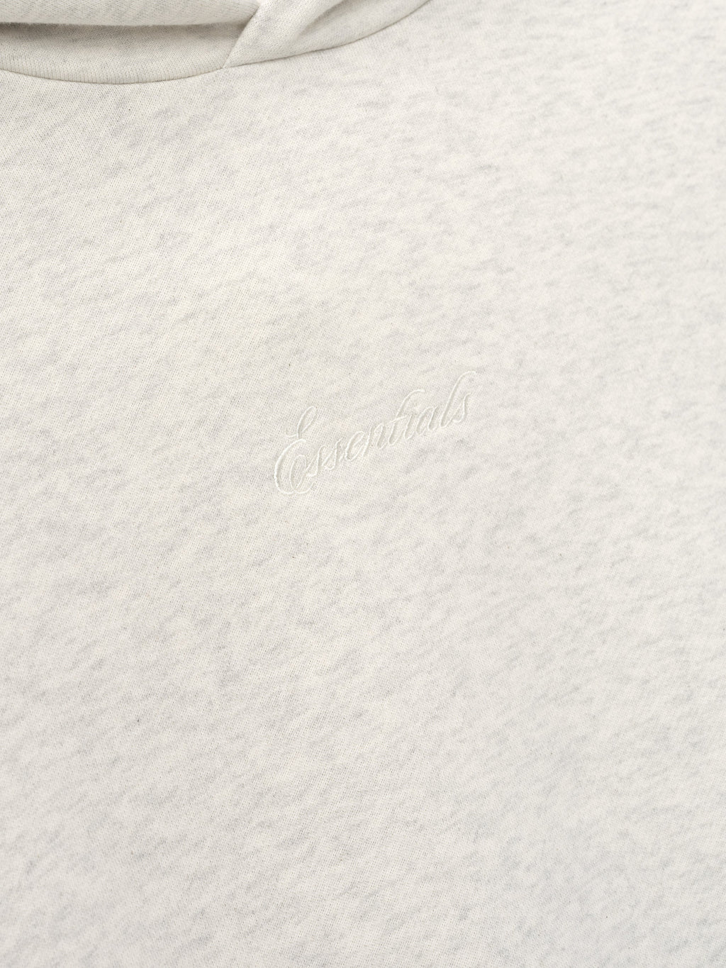 Close-up of a light gray textured fabric with essentials embroidery 