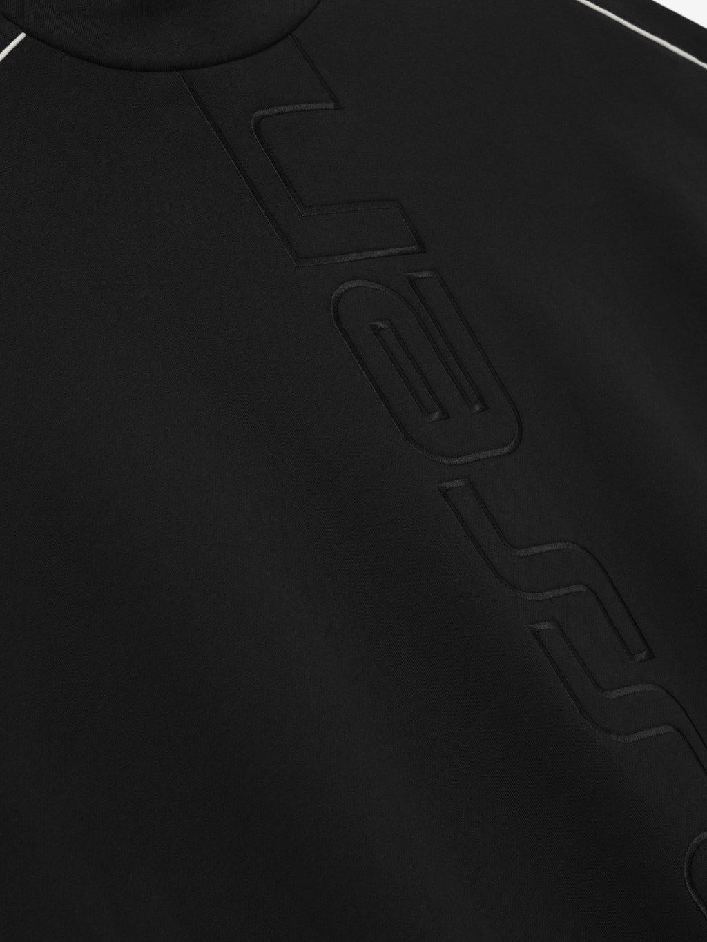 Close-up of a black sweater with essentials embroidered logo.