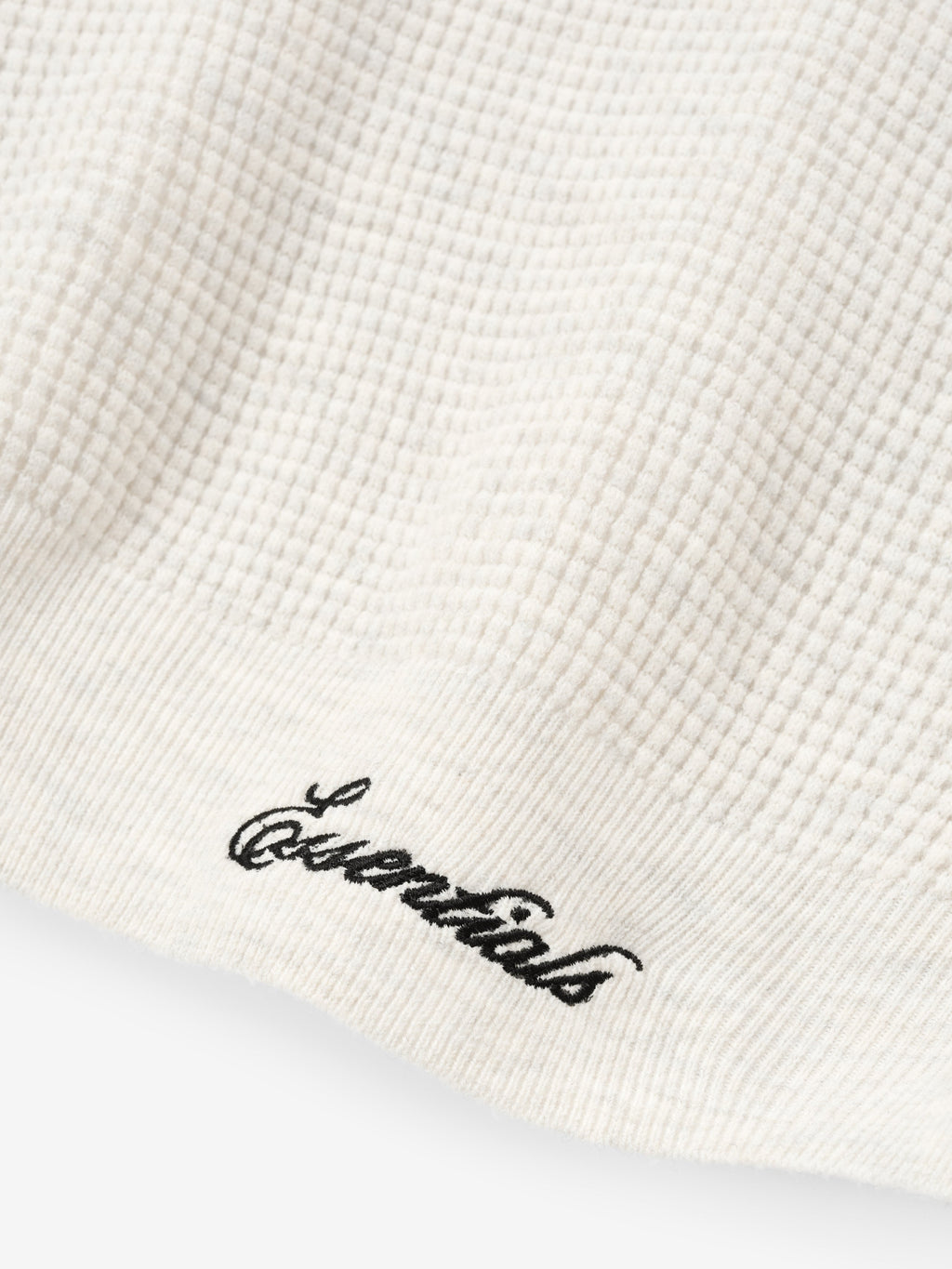 White textured fabric with 'Essentials' embroidery on a white background