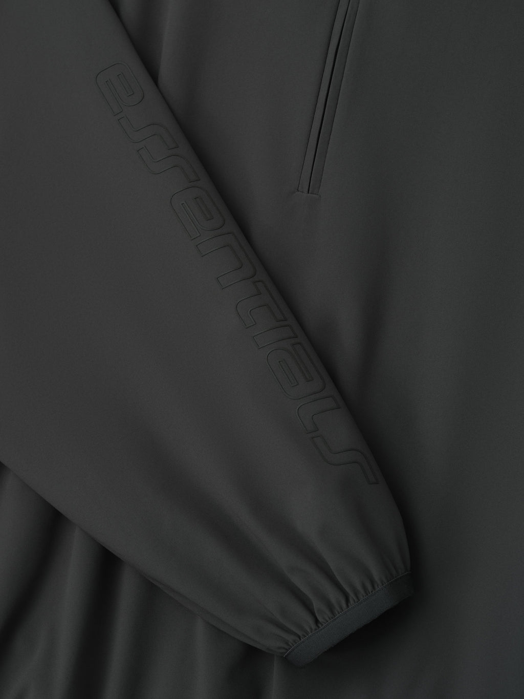 Close-up of womens iron grey nylon half zip track jacket sleeve with embossed Essentials logo and elastic cuff detail gallery 0