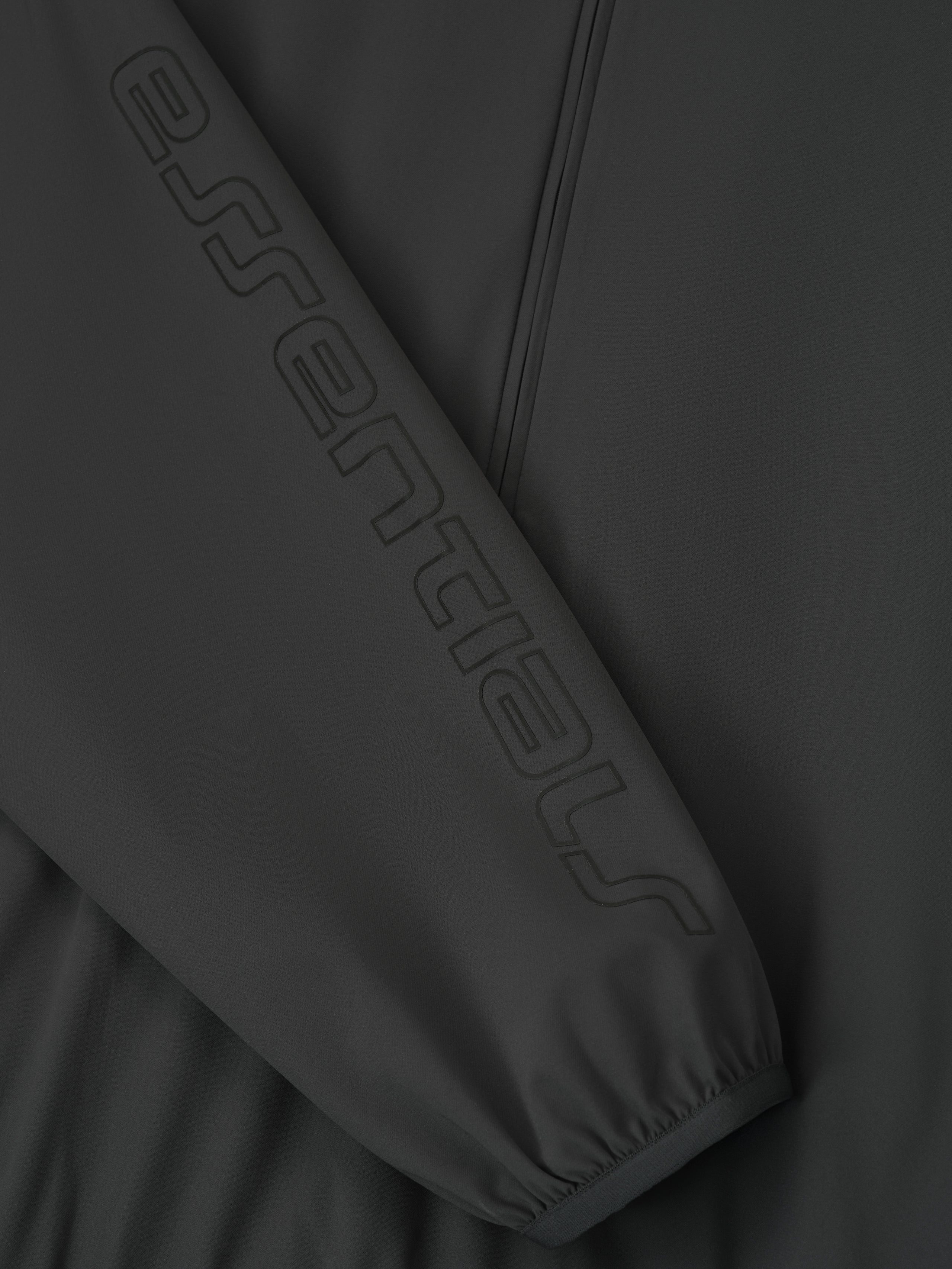 Close-up of iron grey Tech Nylon Half Zip Track Jacket sleeve featuring tonal embossed Essentials logo, gallery position 0
