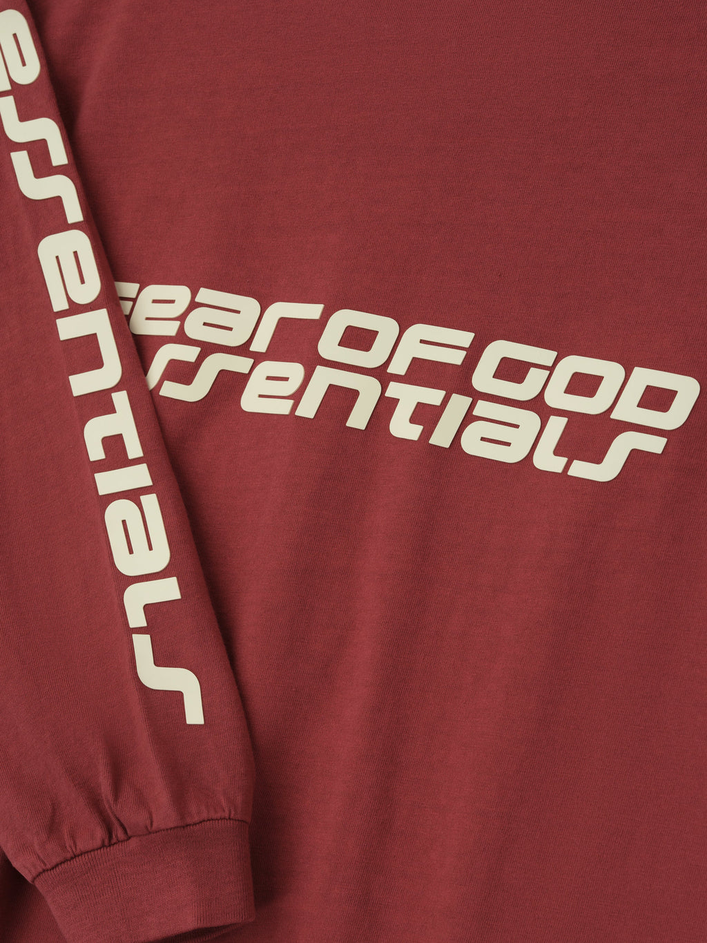 Close-up of crimson Kids Classic Long Sleeve Tee featuring bold Fear of God Essentials print across chest and down sleeve