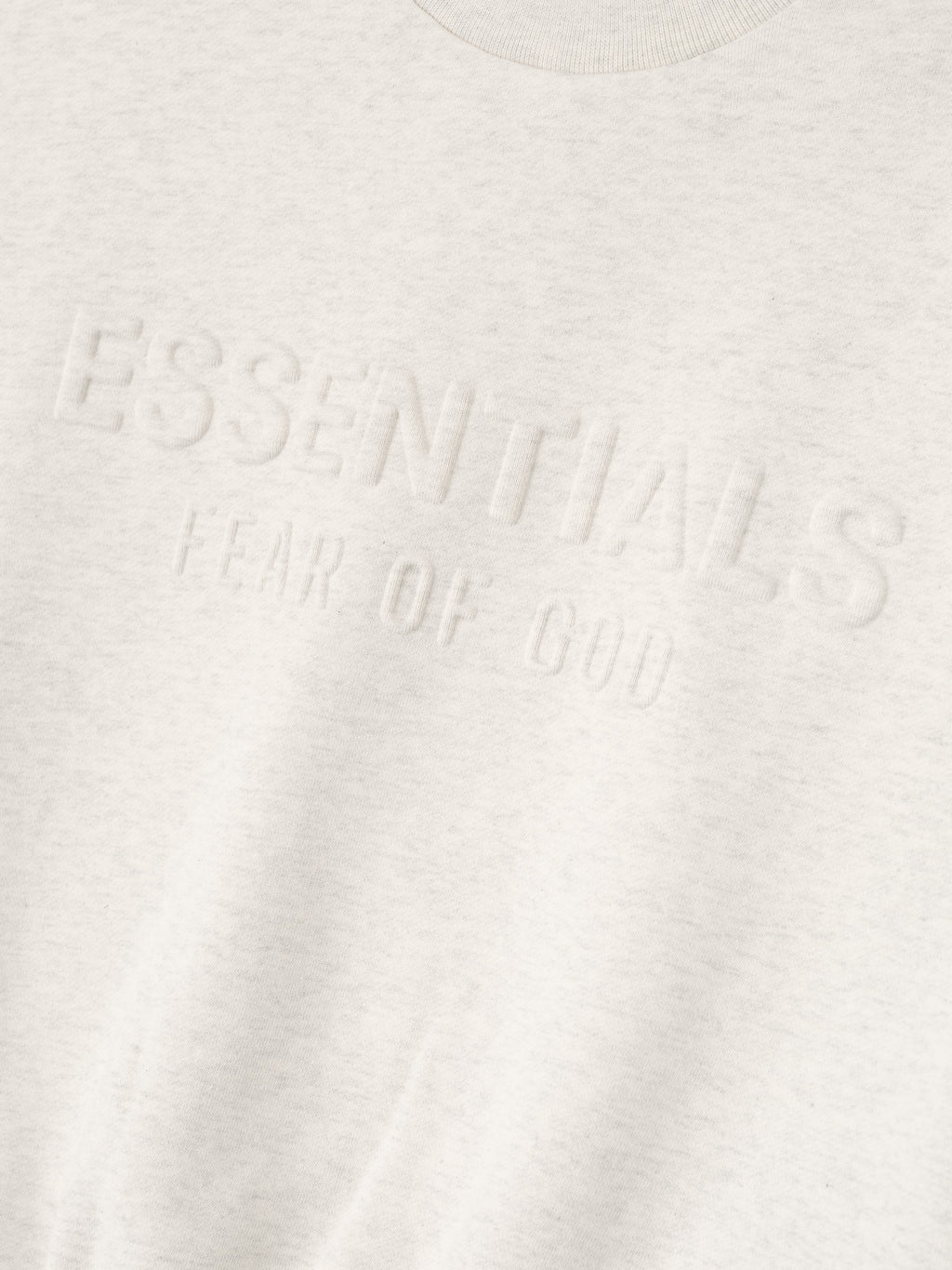 Close-up of oatmeal heather kids sweatshirt showing embossed ESSENTIALS fear of God logo on soft fabric, gallery position 0