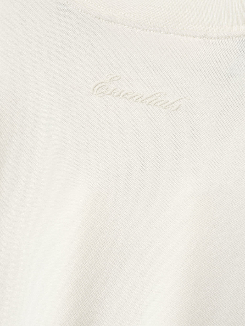 close-up of off-white cotton blend jersey fabric with subtle puff-printed Essentials logo at back neckline