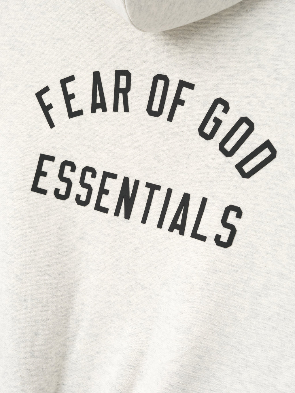 close-up of light grey kids hoodie with Fear of God Essentials logo printed in arched bold black text