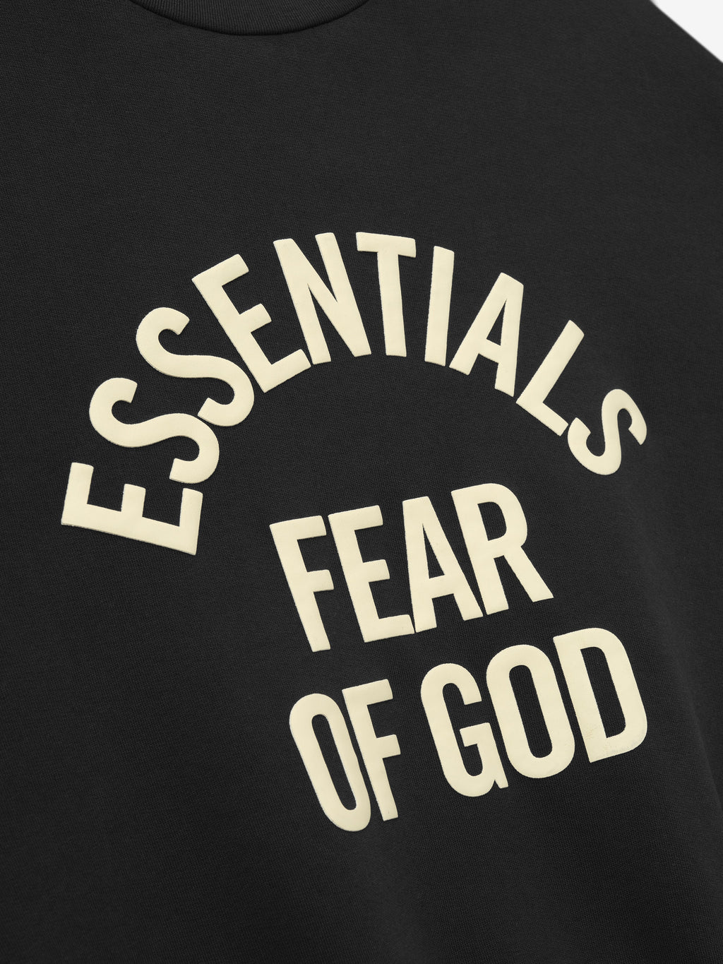 close-up of black crewneck sweatshirt with arched Essentials Fear of God logo printed in cream text on front