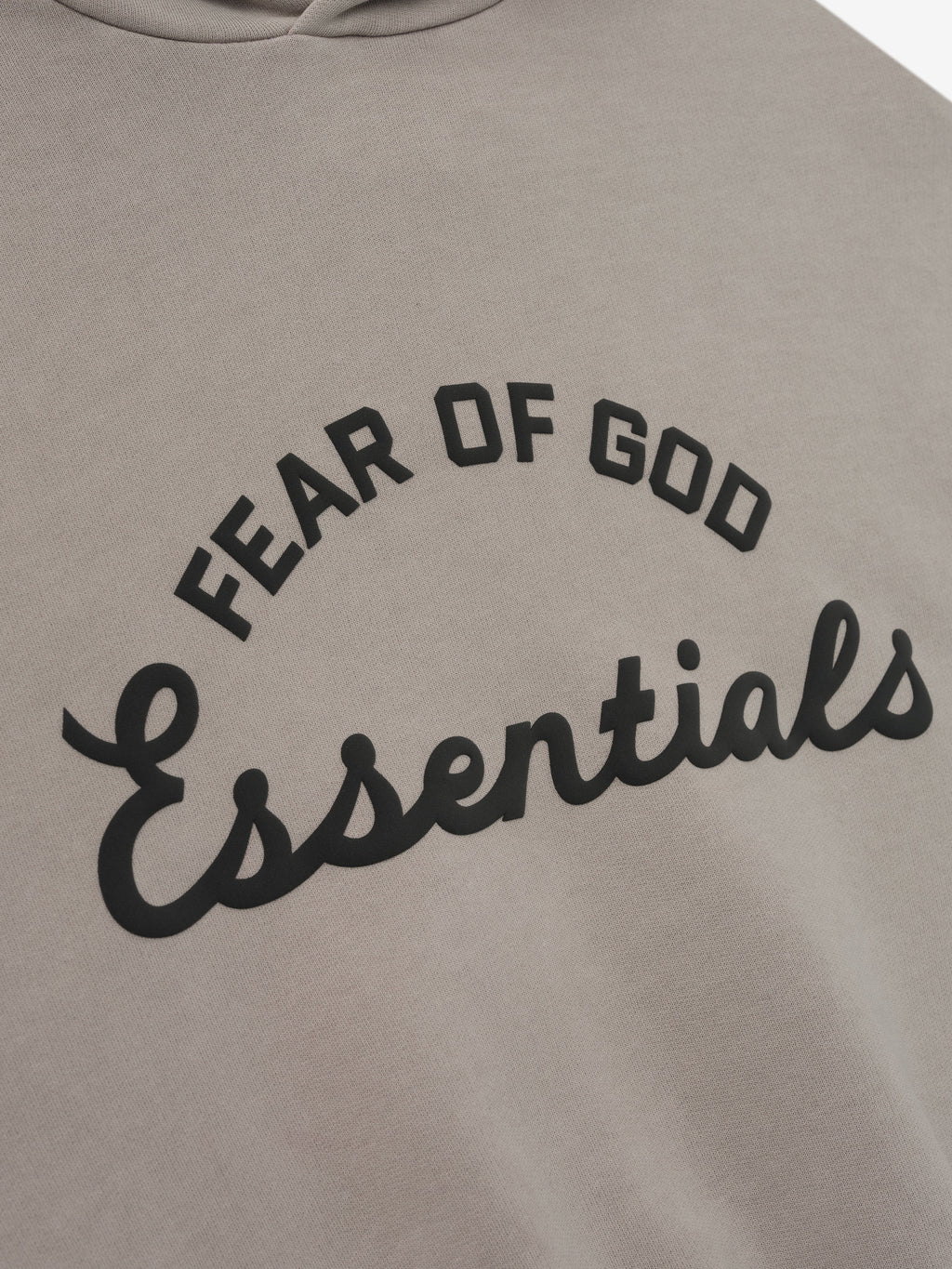 close-up of muted taupe kids hoodie with curved Fear of God Essentials logo printed in black on front