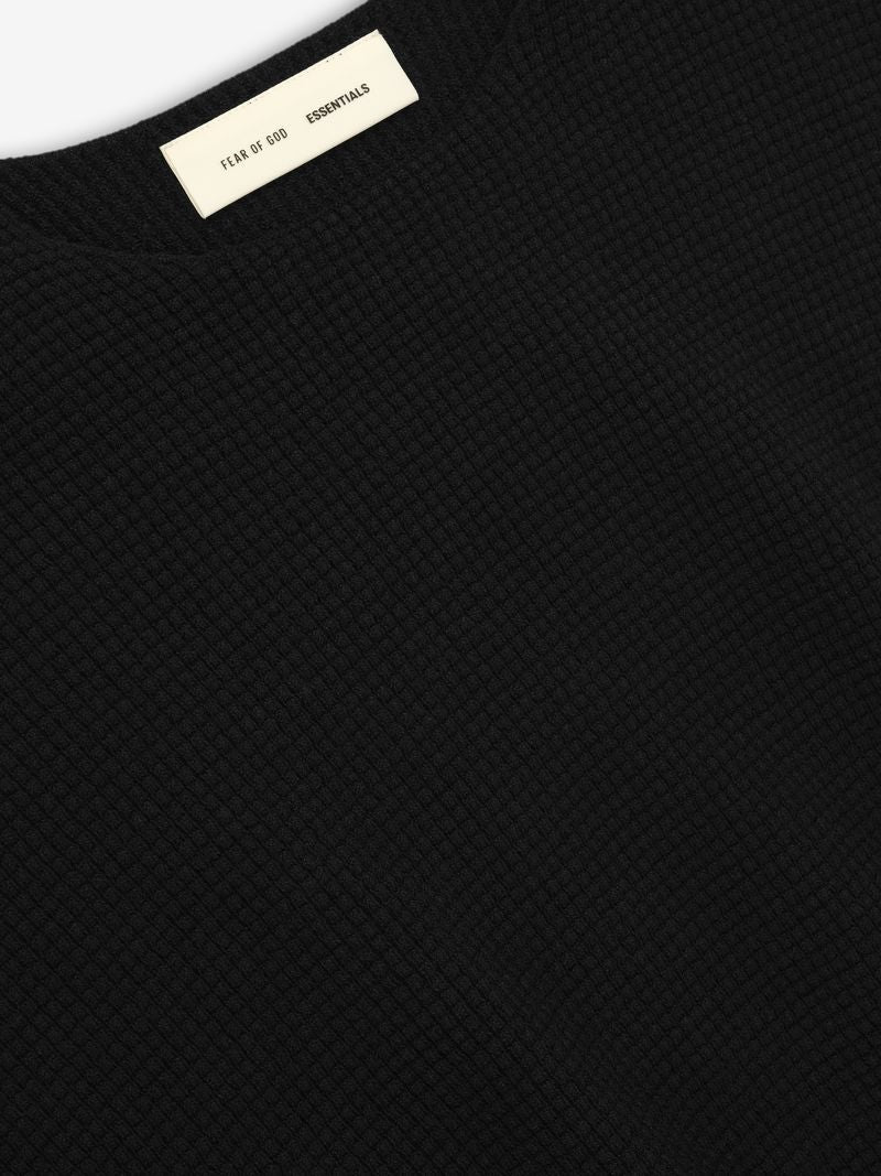 Close-up of black Waffle Crewneck 90s Sweater fabric texture with Fear of God Essentials neck label visible, gallery first shot