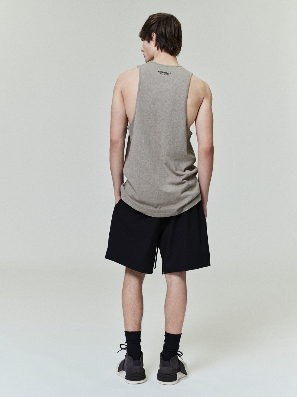 Rear view of model wearing black Sporty Nylon Classic Shorts with sleeveless gray tank top on neutral background