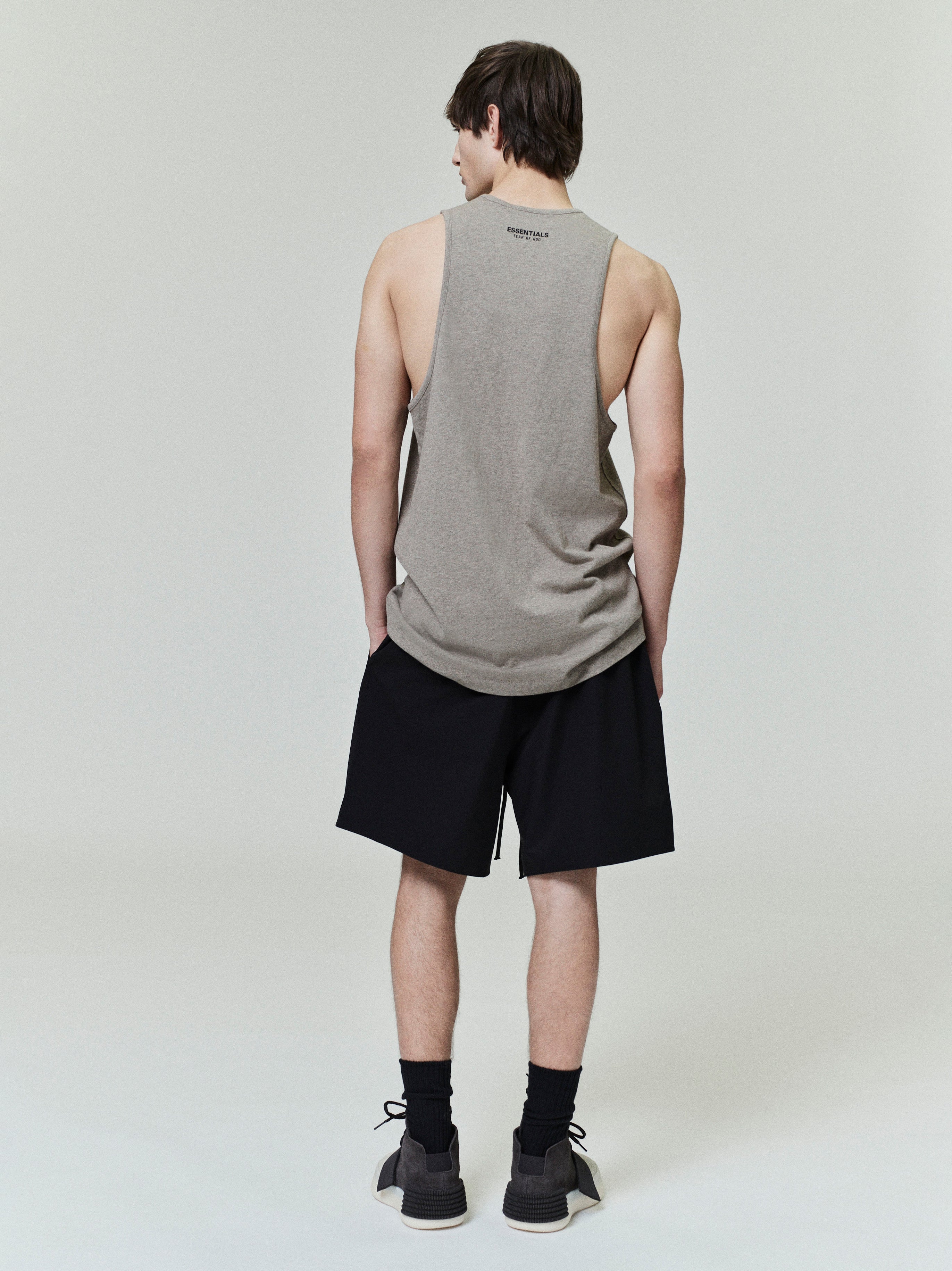 Rear view of model wearing black Sporty Nylon Classic Shorts with sleeveless gray tank top on neutral background