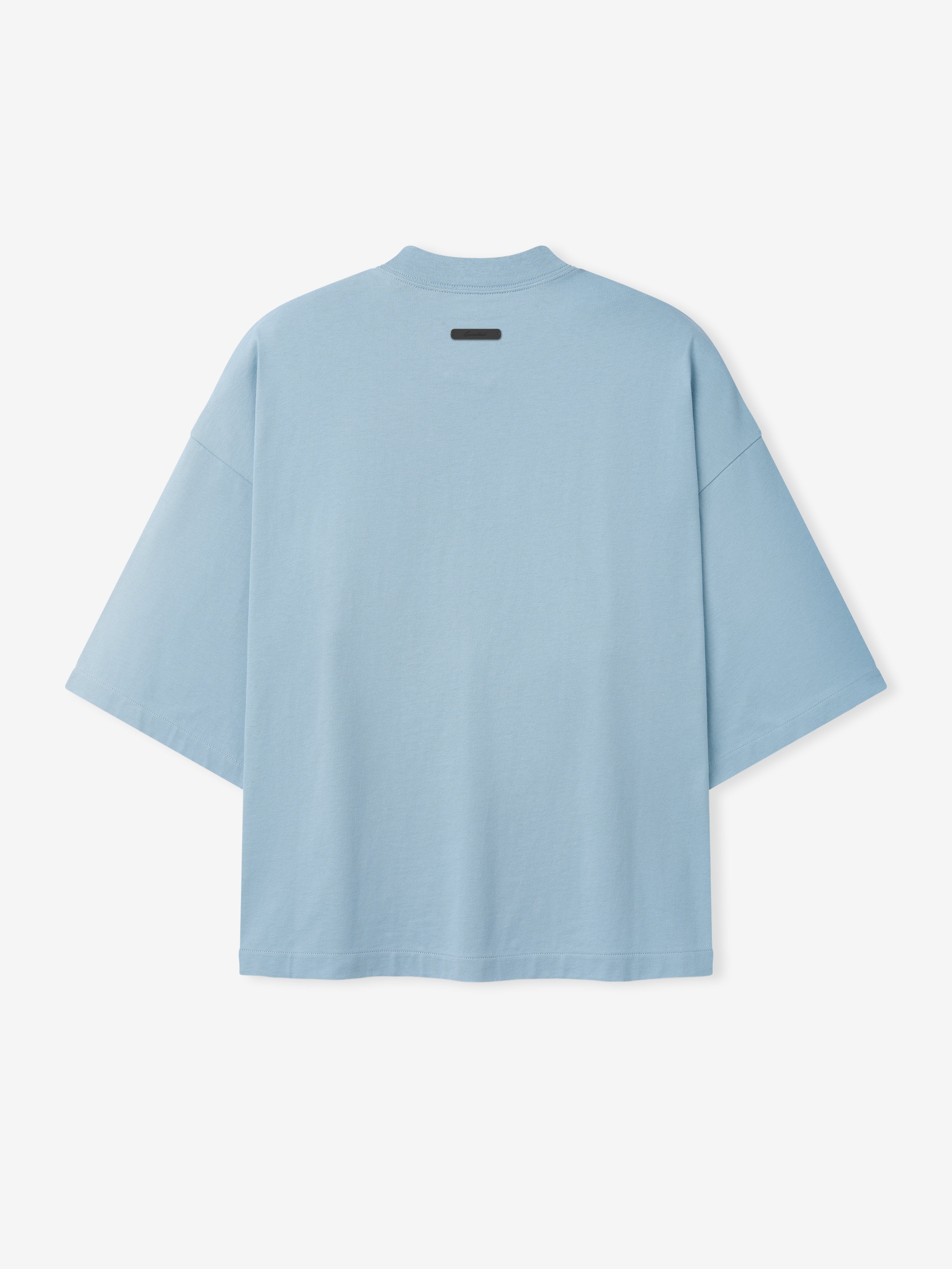 Back view of oversized light blue short-sleeve T-shirt with dropped shoulders and small black label near neckline