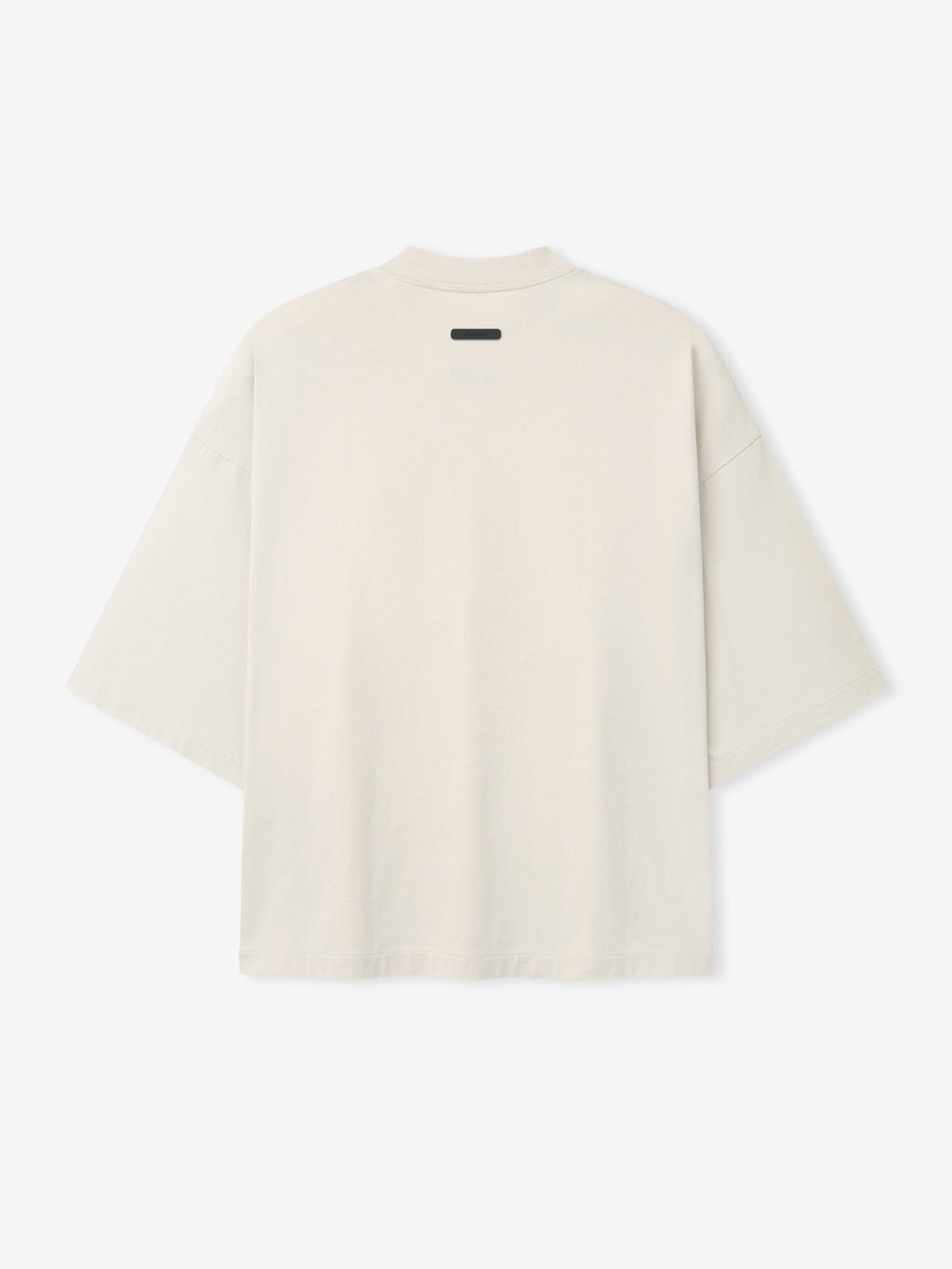 Back view of oversized light beige short-sleeve T-shirt with dropped shoulders and small black label near neckline