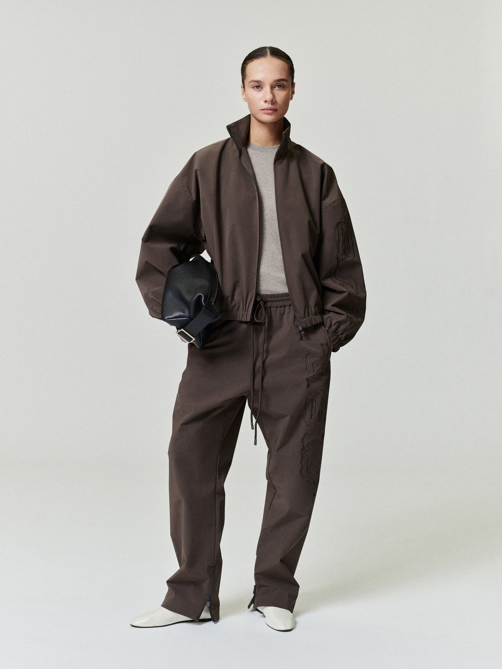 woman wearing brown relaxed straight-leg track pants with elastic waistband and front drawstring closure