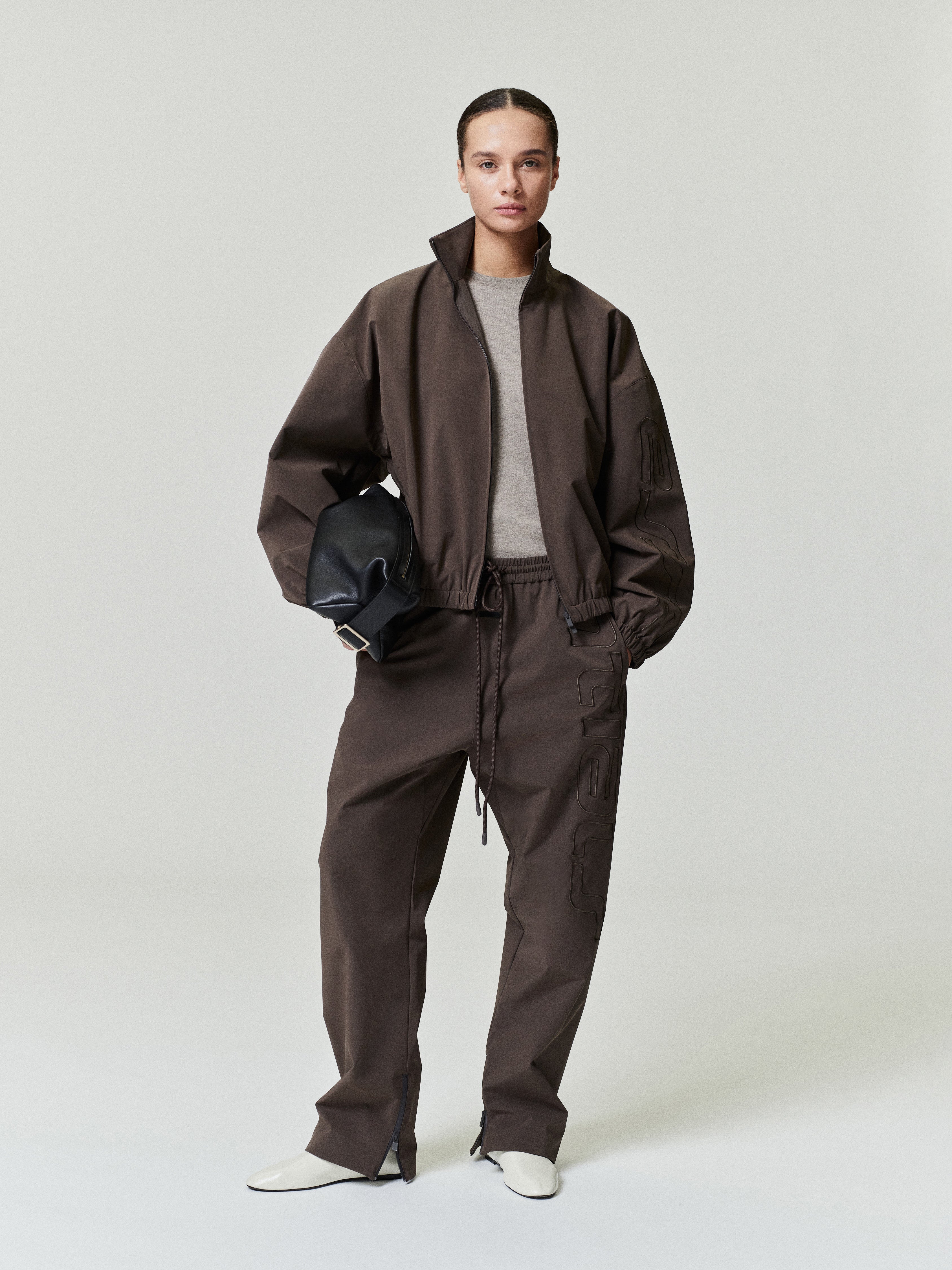 woman wearing brown relaxed straight-leg track pants with elastic waistband and front drawstring closure