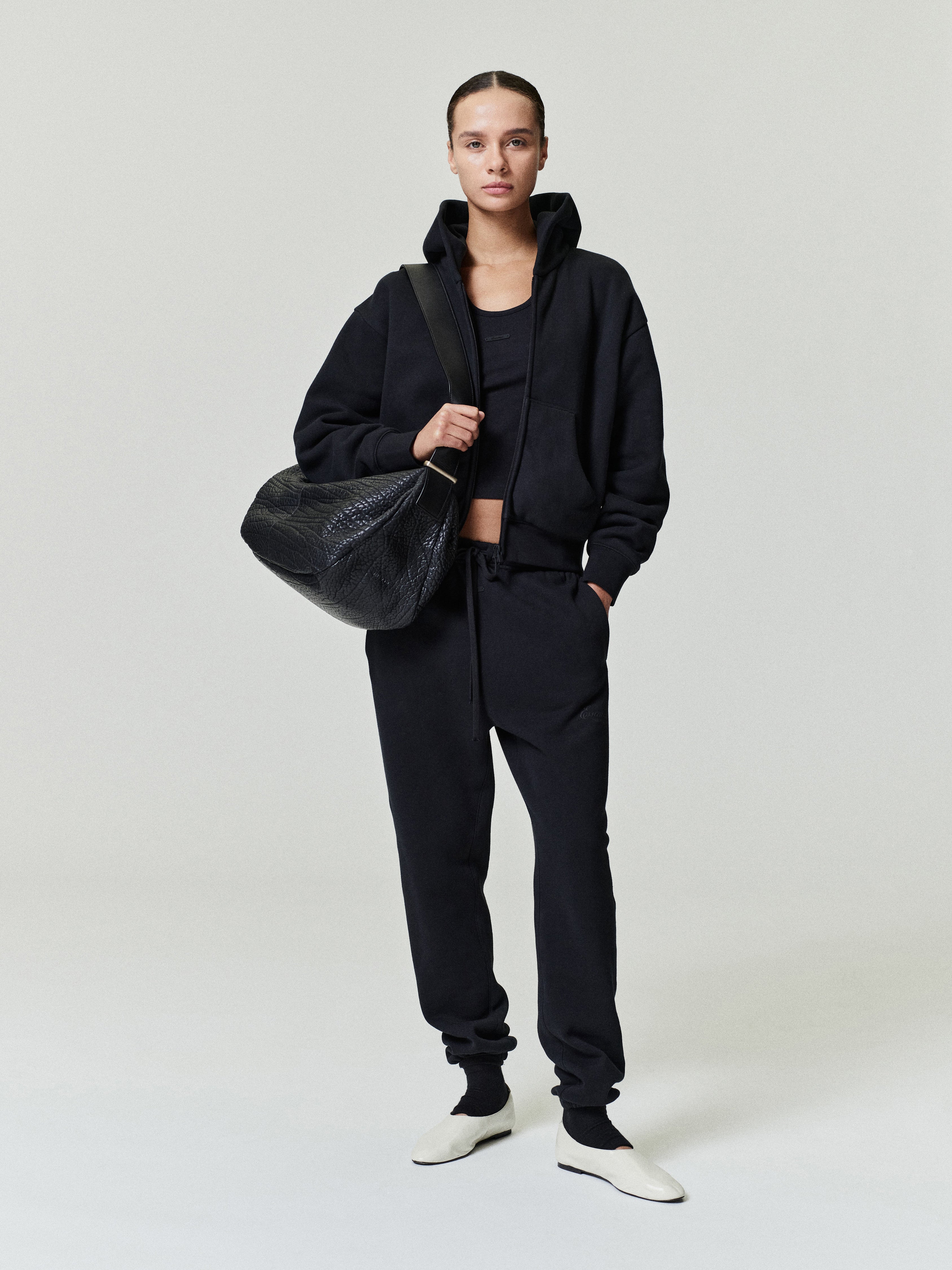 woman wearing black vintage core fleece sweatpants with relaxed fit, elastic hem, and matching black zip-up jacket