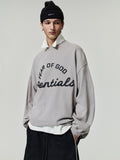 Person wearing a gray 'Fear of God Essentials' sweatshirt on a plain background