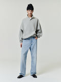 man wearing vintage wash straight leg denim 5-pocket jeans with gray pullover and black beanie