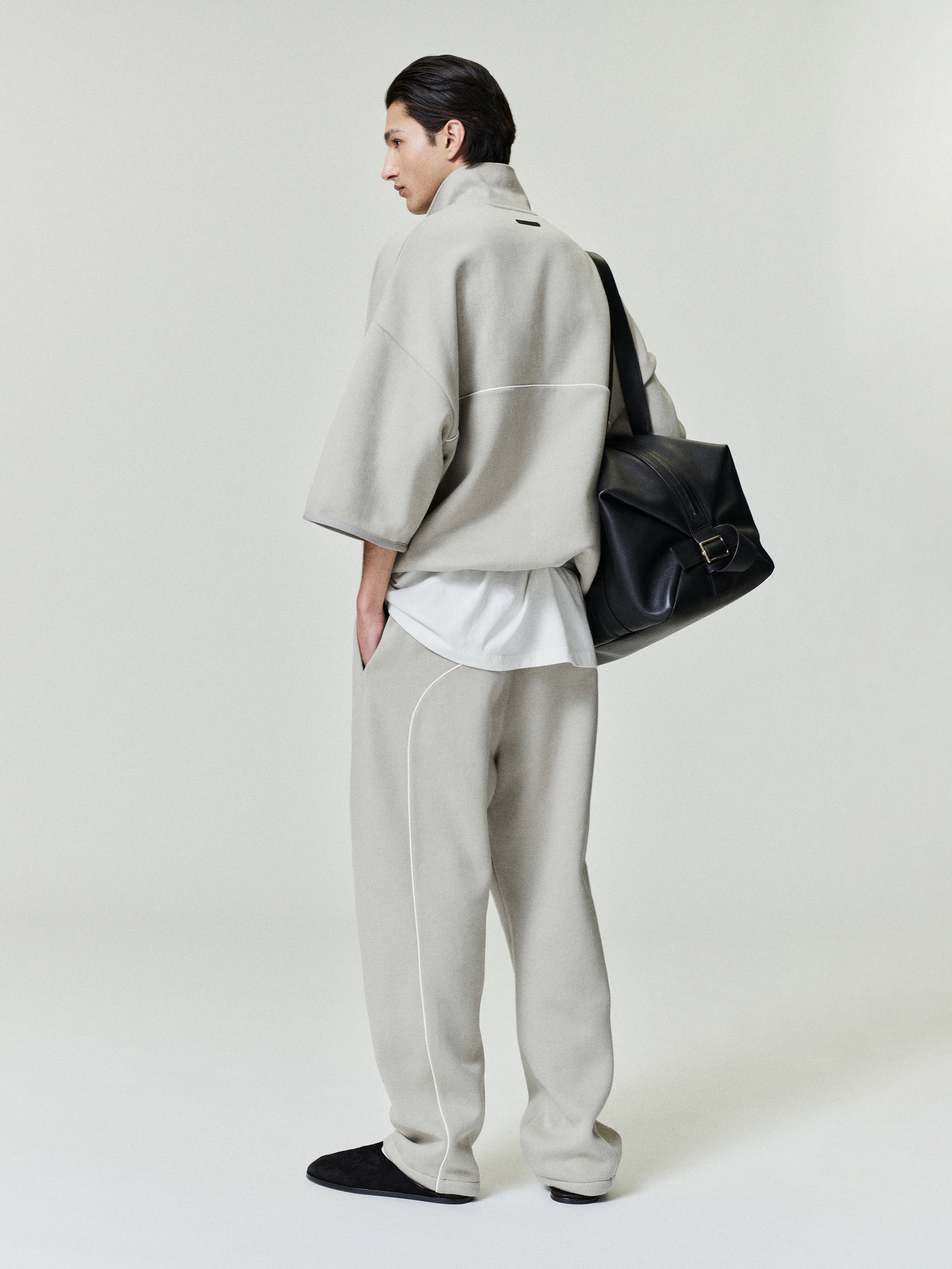 man wearing light grey baggy sweatpants with white sportswear piping and relaxed fit paired with matching top