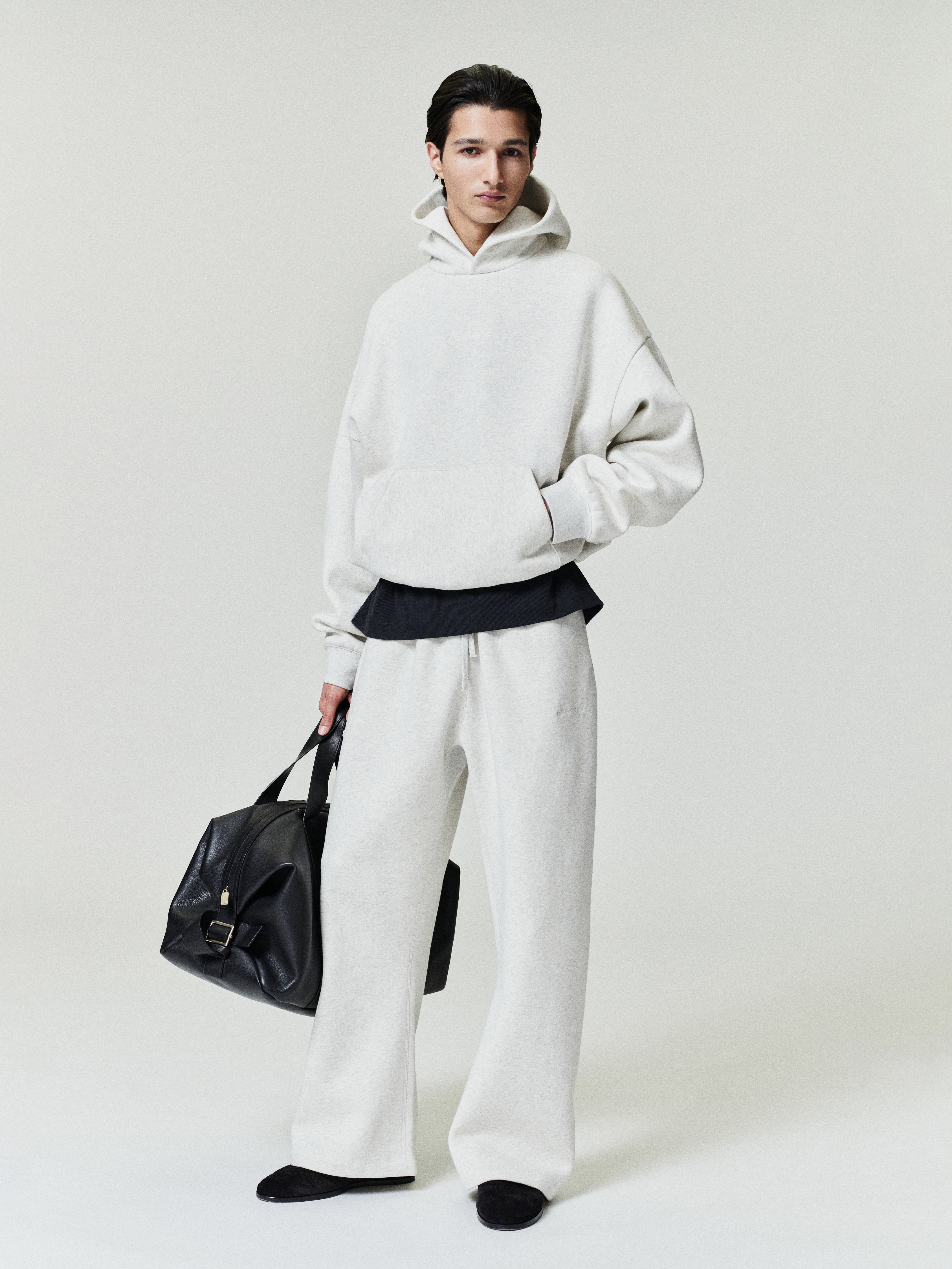 model wearing off-white relaxed fit flare sweatpants with drawstring waistband and matching oversized hoodie