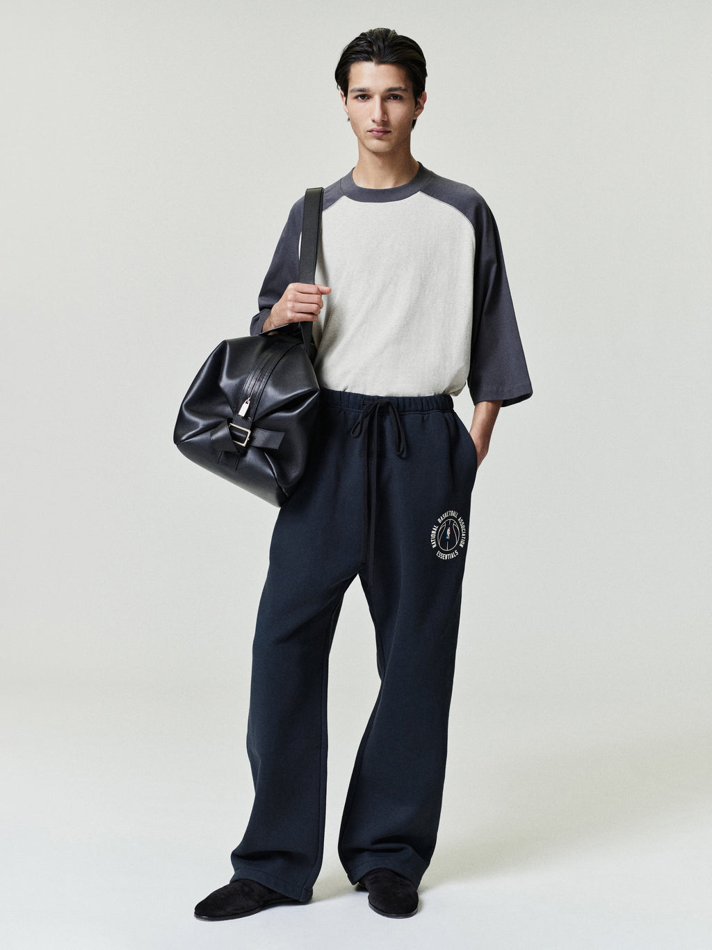 model wearing navy heavyweight cotton fleece sweatpants with relaxed straight leg and NBA x Barkley Hendricks circular logo on thigh