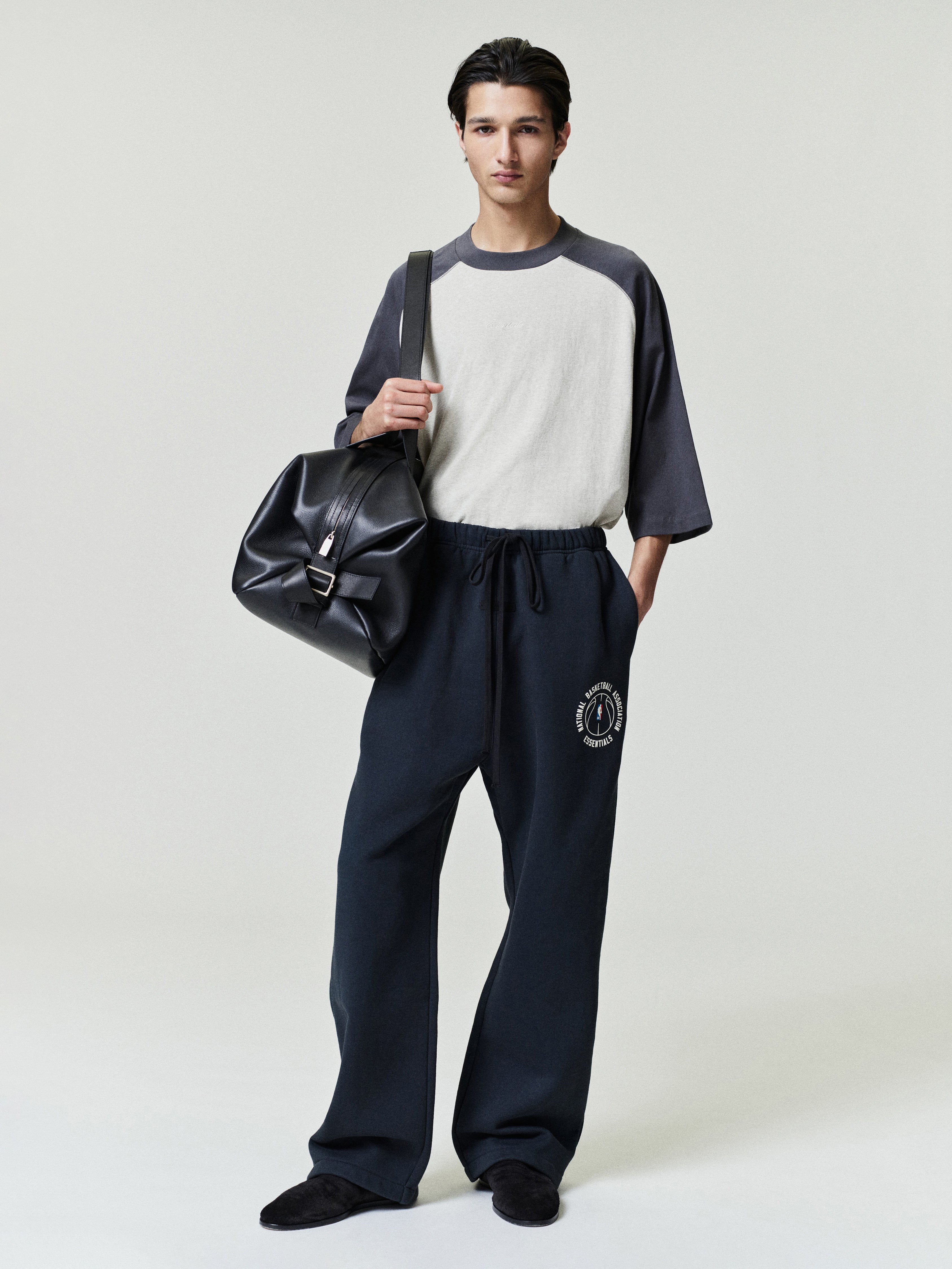 model wearing navy heavyweight cotton fleece sweatpants with relaxed straight leg and NBA x Barkley Hendricks circular logo on thigh