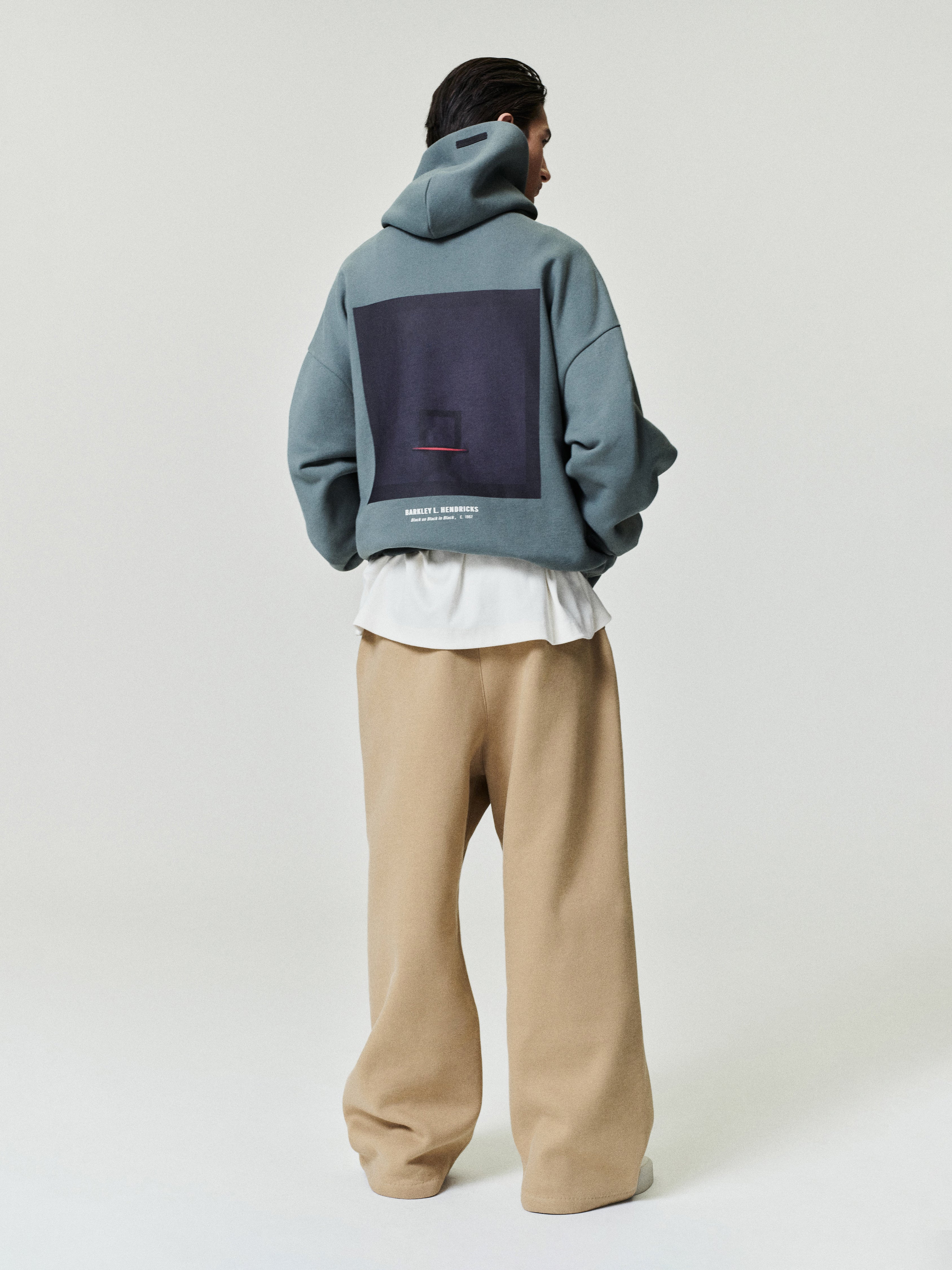 muted blue oversized hoodie with large square graphic and Barkley Hendricks text on back worn by model facing away