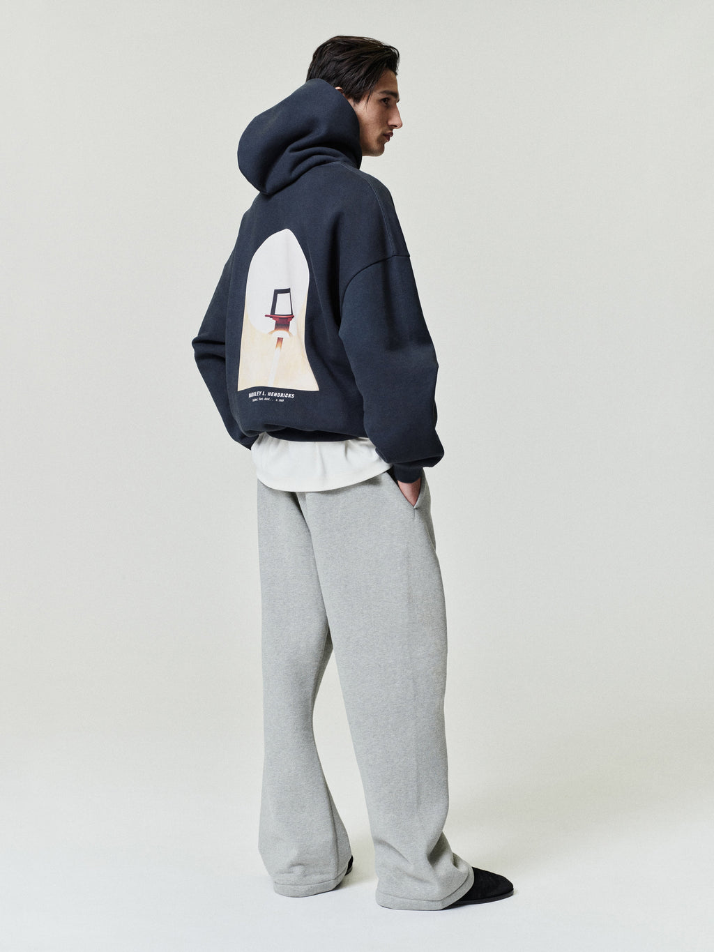 navy heavyweight cotton fleece hoodie with large artwork print and Barkley L. Hendricks text on back worn with gray wide-leg pants
