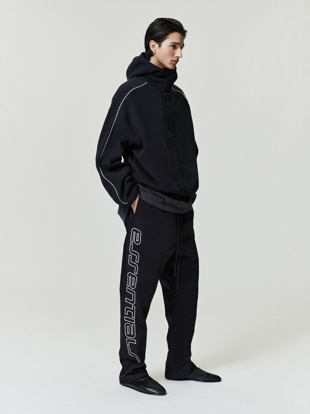 Person wearing a black tracksuit with a brand logo on a white background
