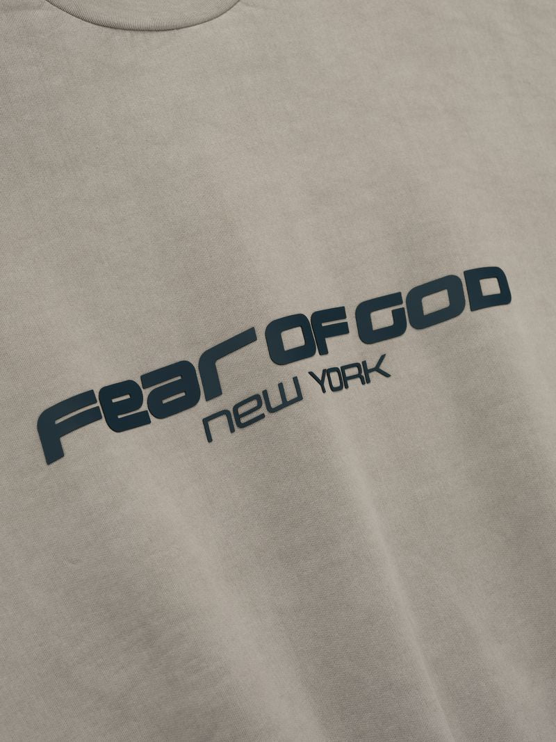 Close-up of black Fear of God New York text printed diagonally on taupe fabric of heavy fleece cropped sweatshirt tKtTMAXQ.jpg